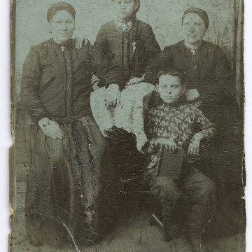 Дві жінки і дівчина у народному вбранні та хлопчик із книгою