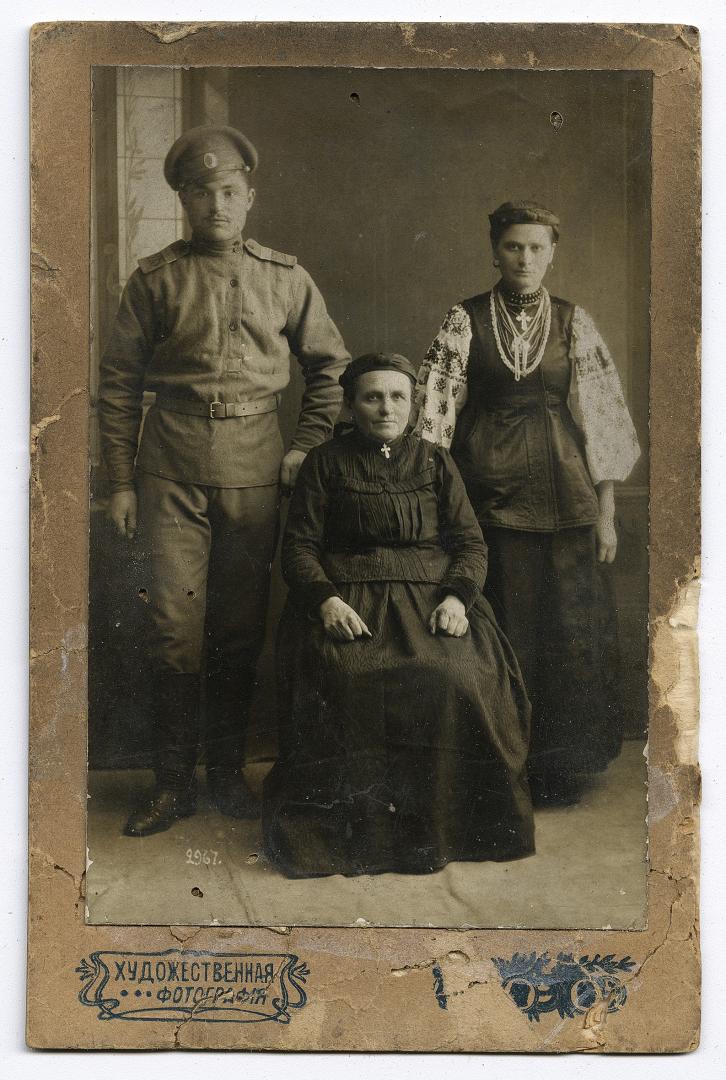 Man in World War I military uniform and two women in traditional attire