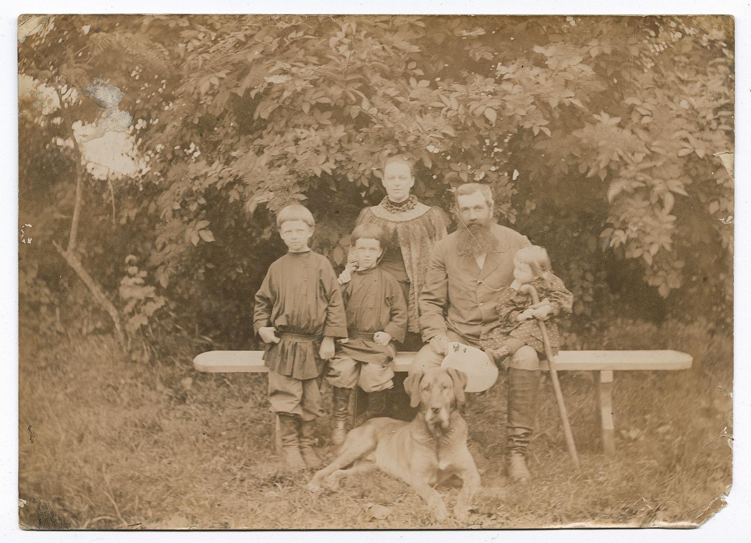 Man holding a child, woman, two boys, and a dog