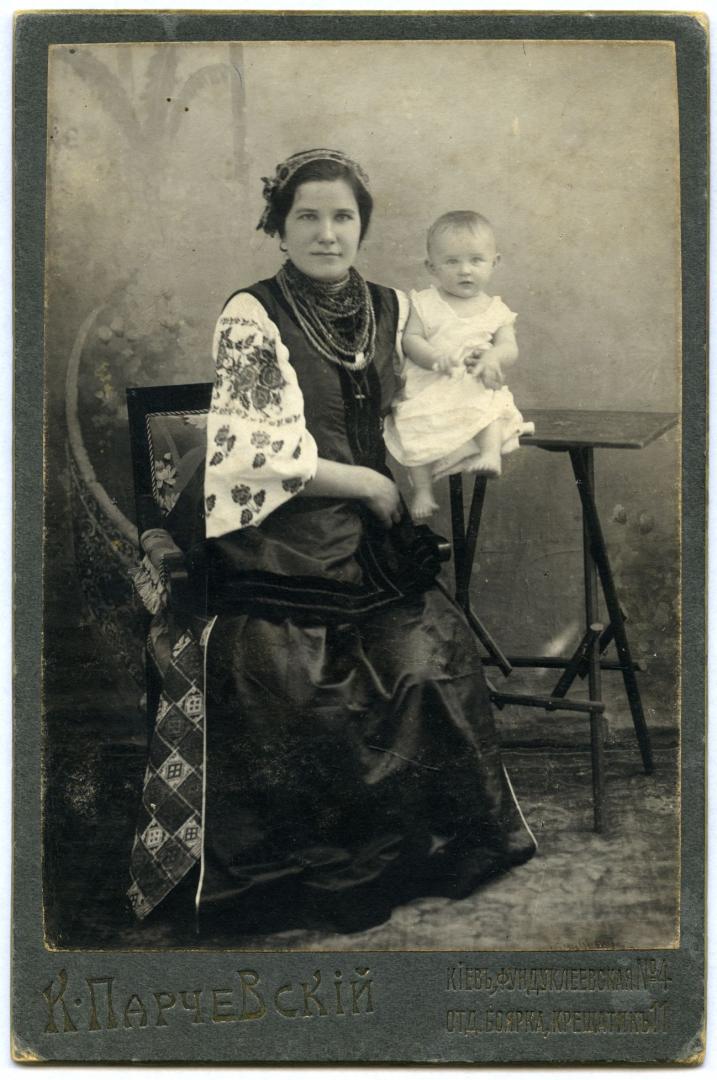 Photo. A woman wearing folk attire holding a child