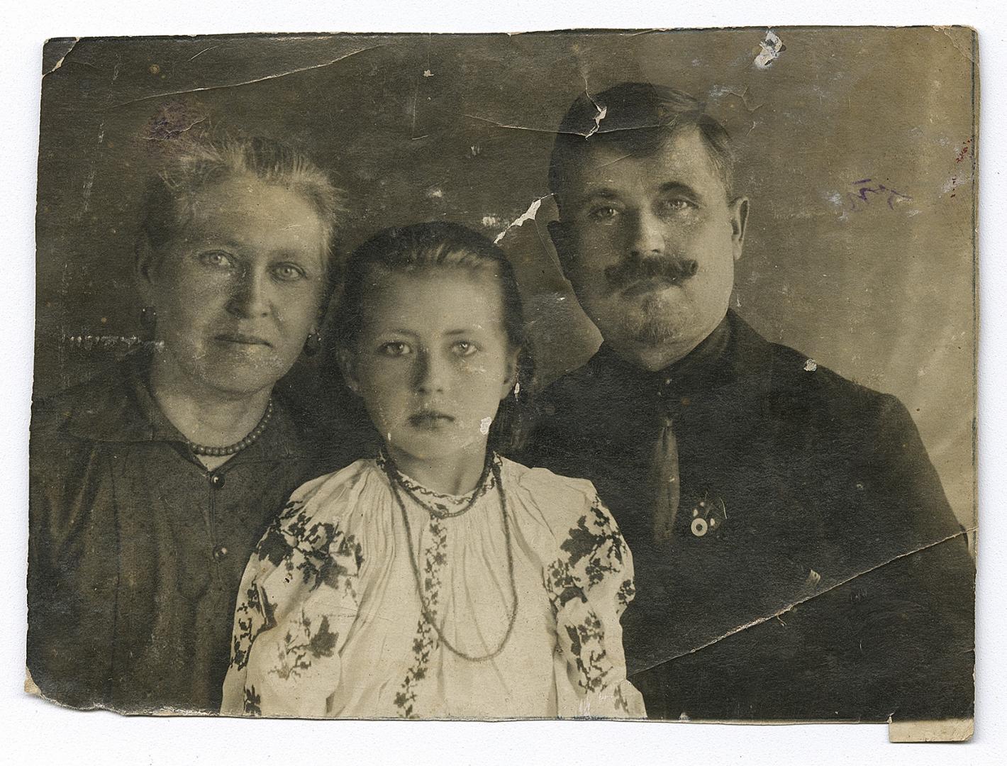 Жінка, дівчинка у вишитій сорочці та чоловік