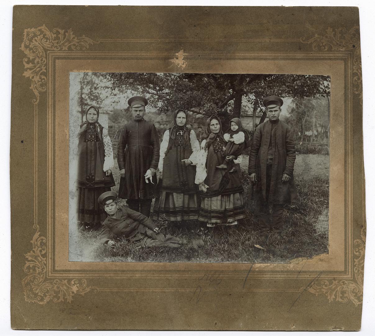 Твоє жінок та дівчинка у народному вбранні та троє чоловіків у кашкетах
