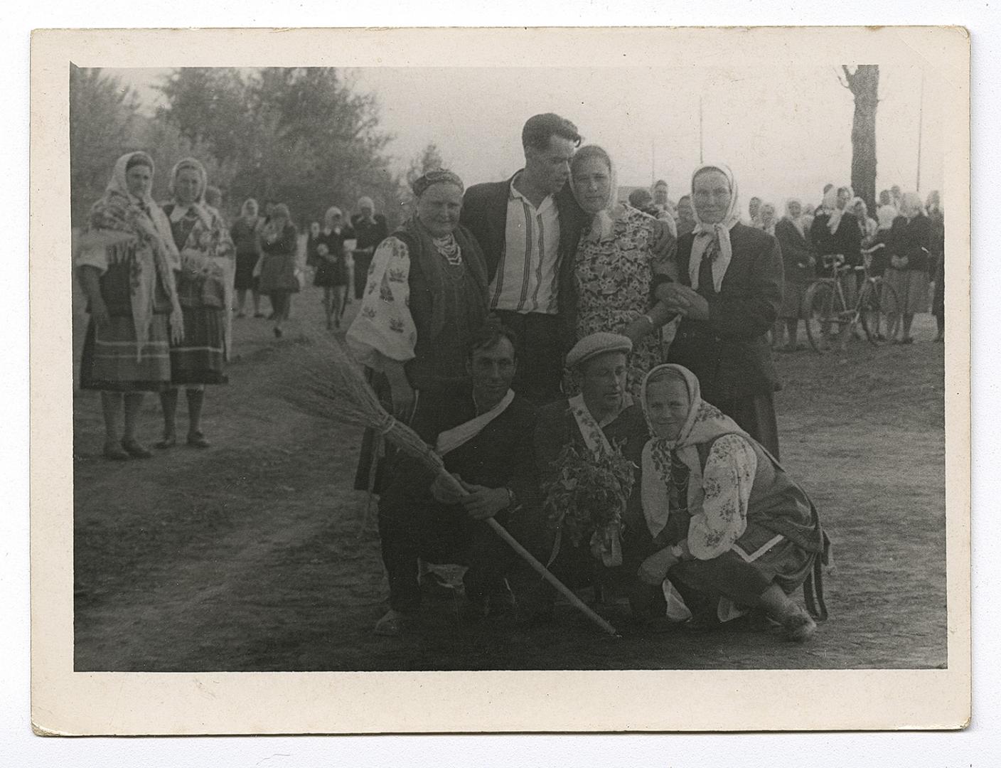 Group of people on a street, with women in traditional attire in the foreground and background