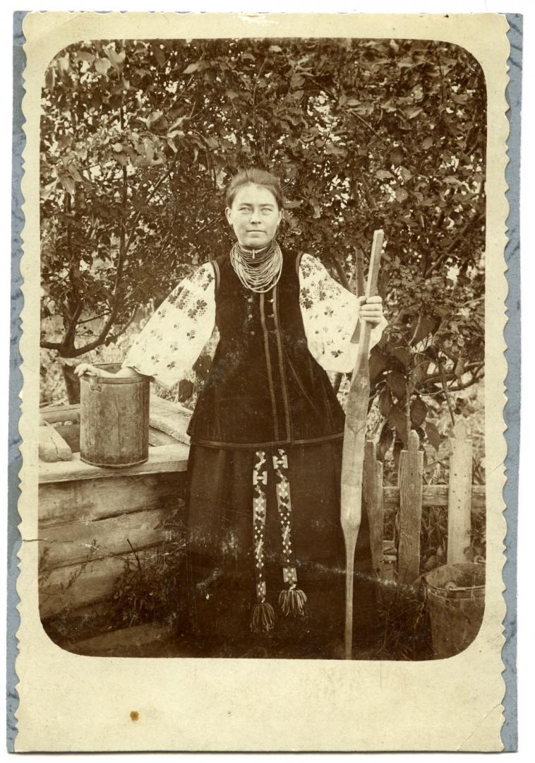 Photo. A girl wearing folk attire near a well