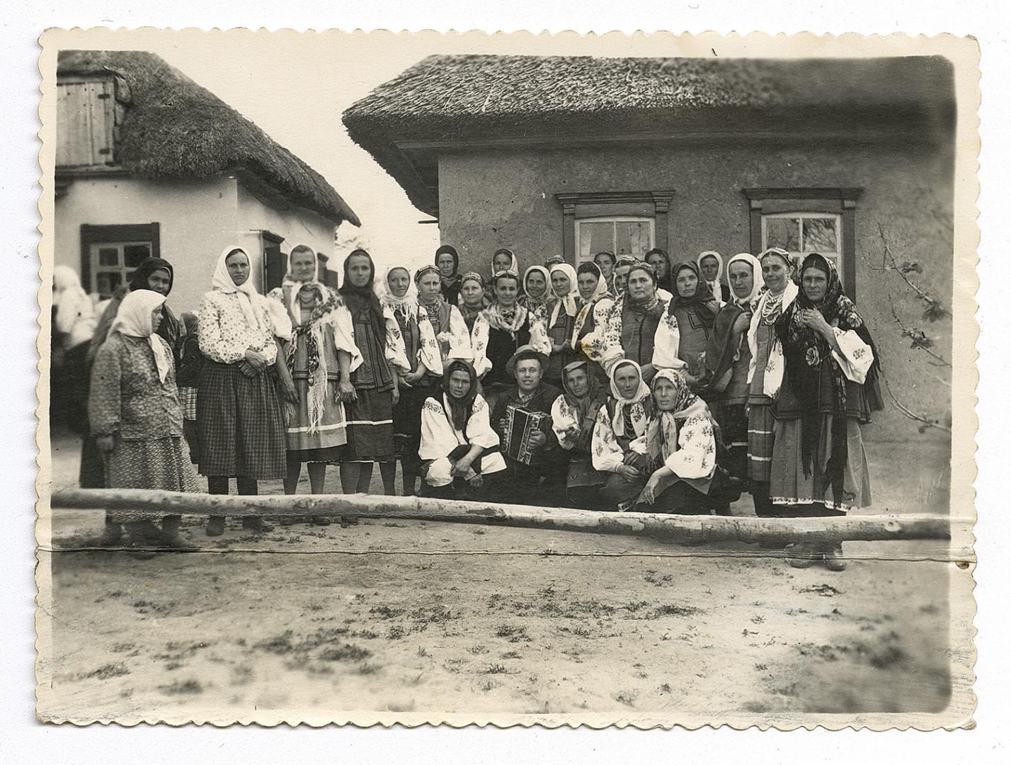 Гурт жінок у народному вбранні та чоловік-гармоніст