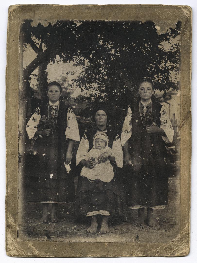 Жінка з немовлям на руках та дві дівчини у народному вбранні