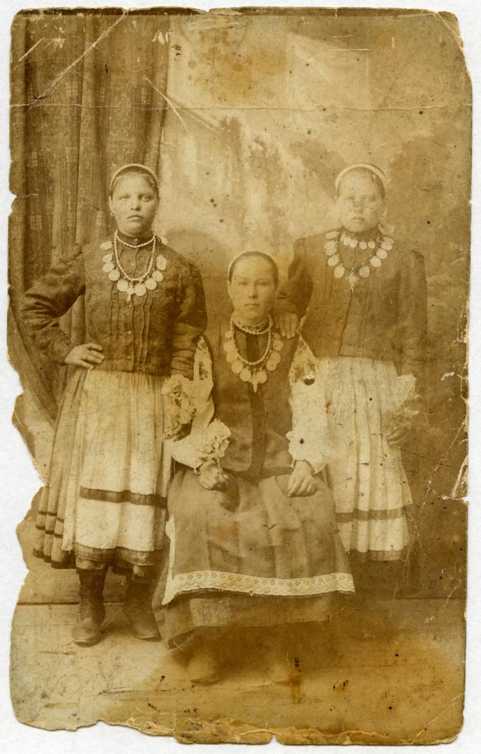 Photo. Three girls wearing folk attire and dukach (necklace with a coin)