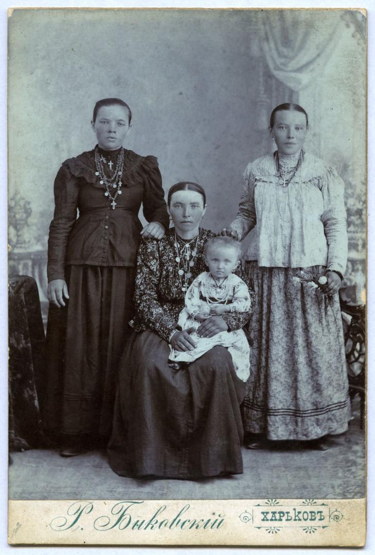 Photo. A mother with a child and two women wearing bourgeois clothes urban upper-middle class attire. 