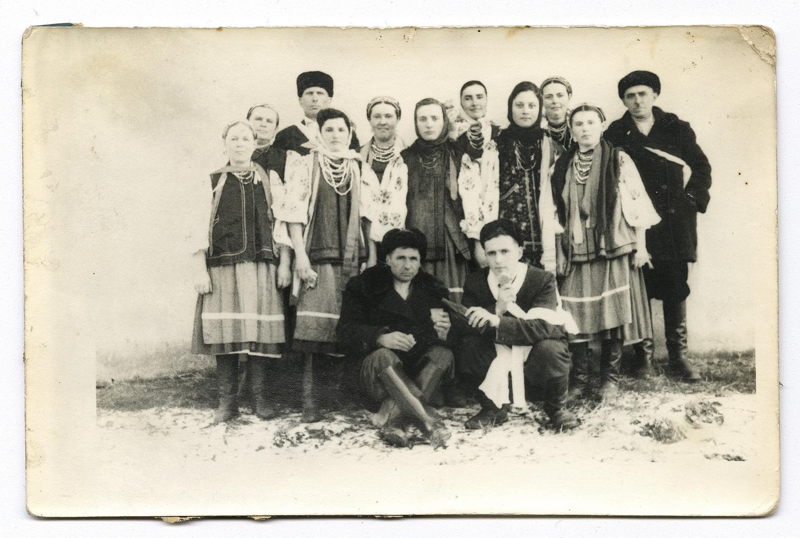 Жінки у традиційному народному вбранні та четверо чоловіків, троє перев'язані рушниками