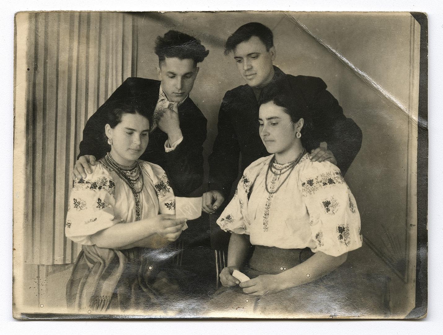 Дві дівчини у вишитих сорочках та двоє хлопців, один у вишитій сорочці під верхнім одягом