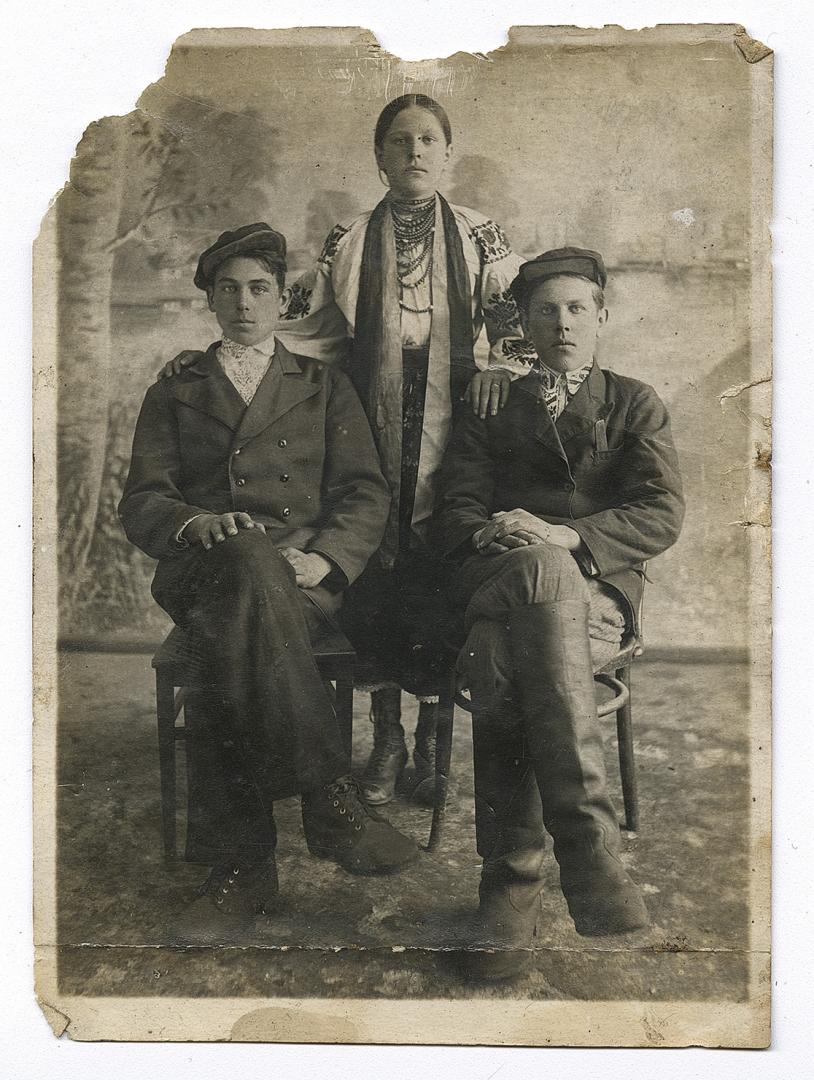 Two boys in embroidered shirts under outerwear and a girl in traditional attire