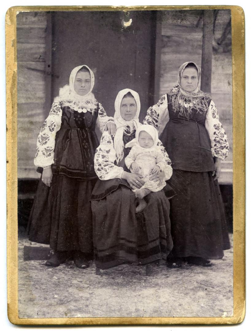 Photo. A mother with her baby and two young women wearing folk attire