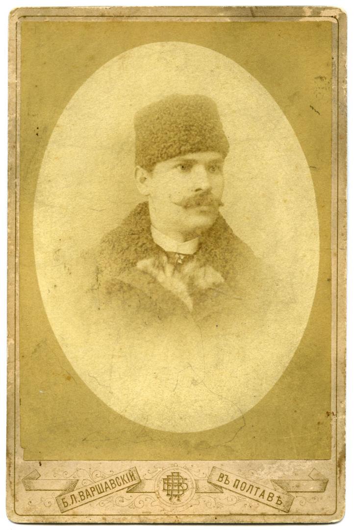 Погрудний фотопортрет молодого чоловіка у пальті з каракулевим коміром