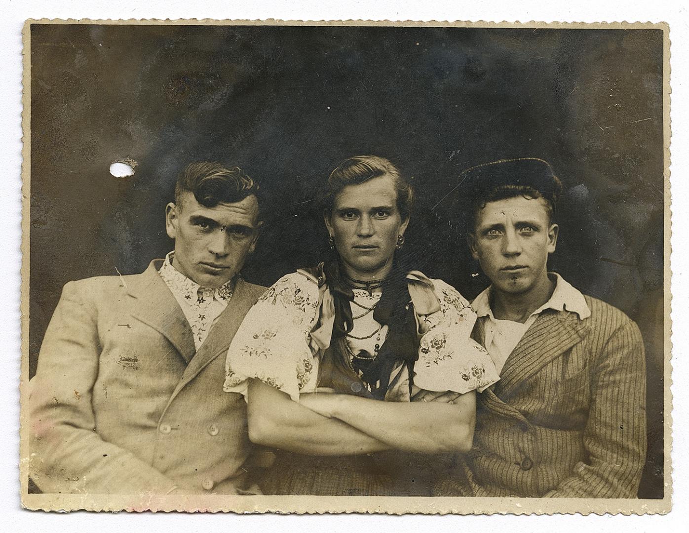 Girl in traditional attire and two boys, one wearing an embroidered shirt under outerwear