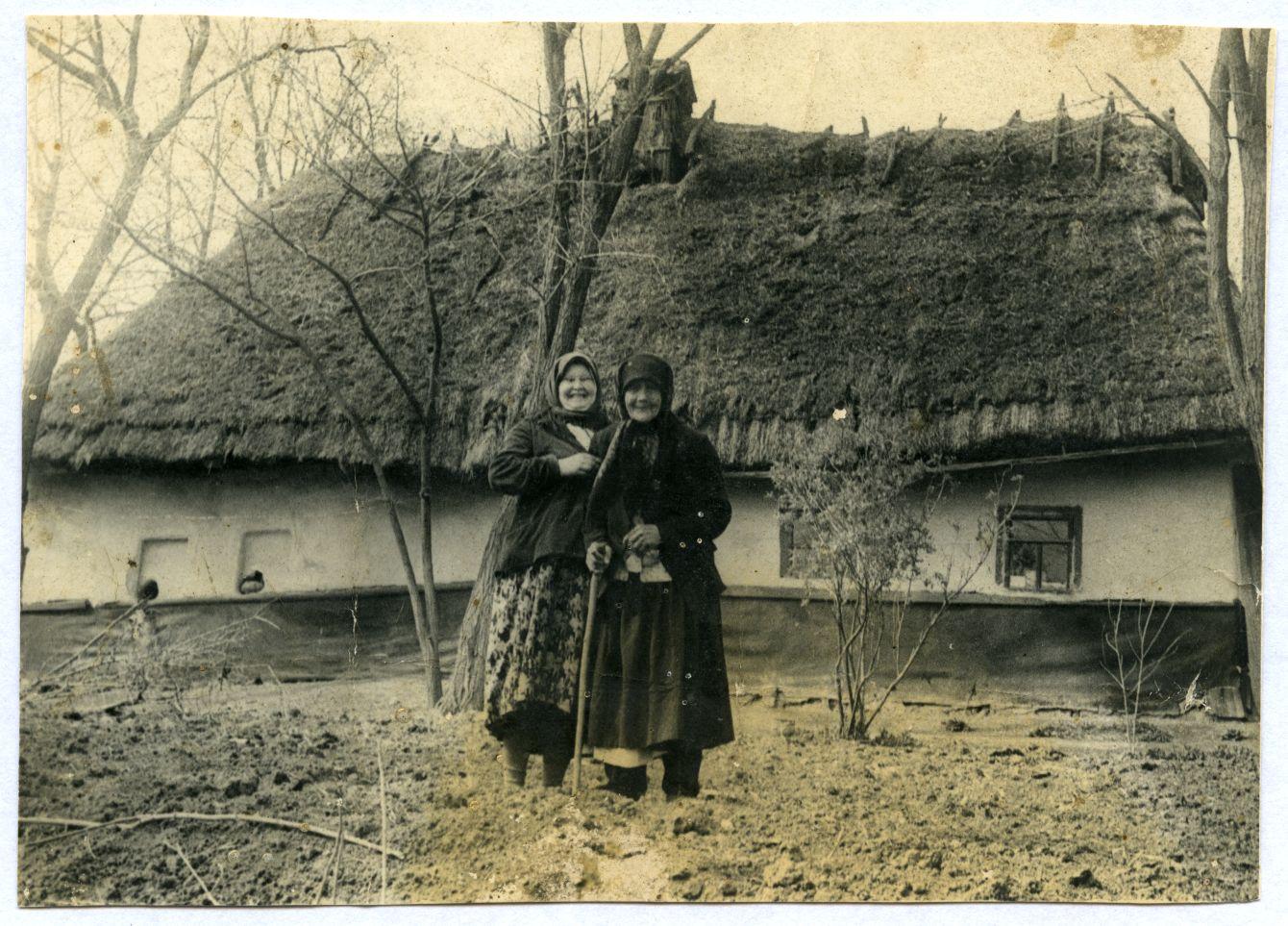 Фото. Тодоска Загоруйко (Микитюк) з дочкою Марією у народному вбранні біля старої хати