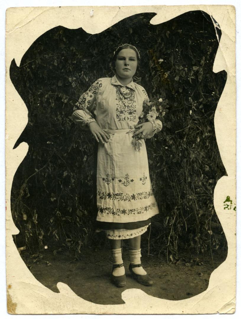 Photo. A girl, Nina Andrushko (Sardan), wearing folk attire with a bouquet of wildflowers