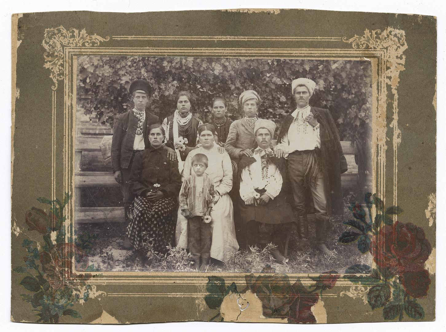 Four men in embroidered shirts under outerwear, two women, two girls in traditional attire, and a boy