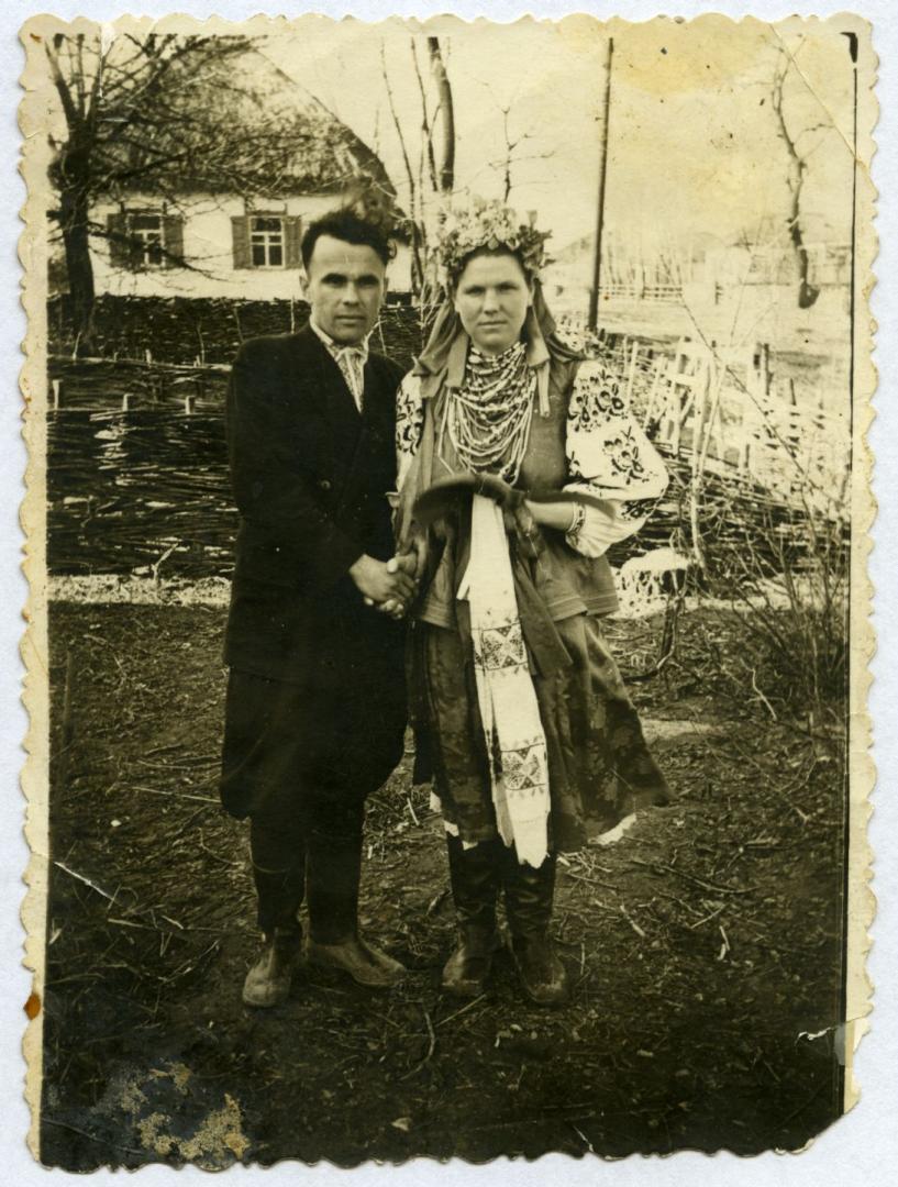 Photo. A bride and a groom holding a kolach [braided bread]