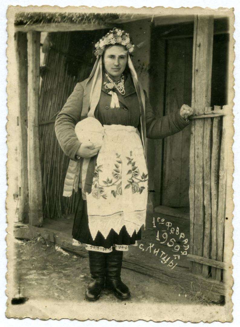 Photo. A bride standing in front of a house wearing a wedding attire