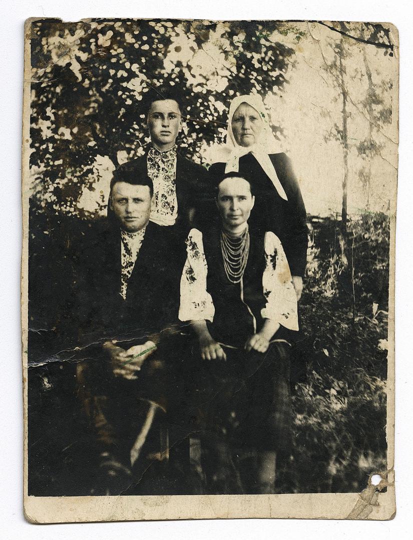 Two men in embroidered shirts under outerwear and two women, one in traditional attire
